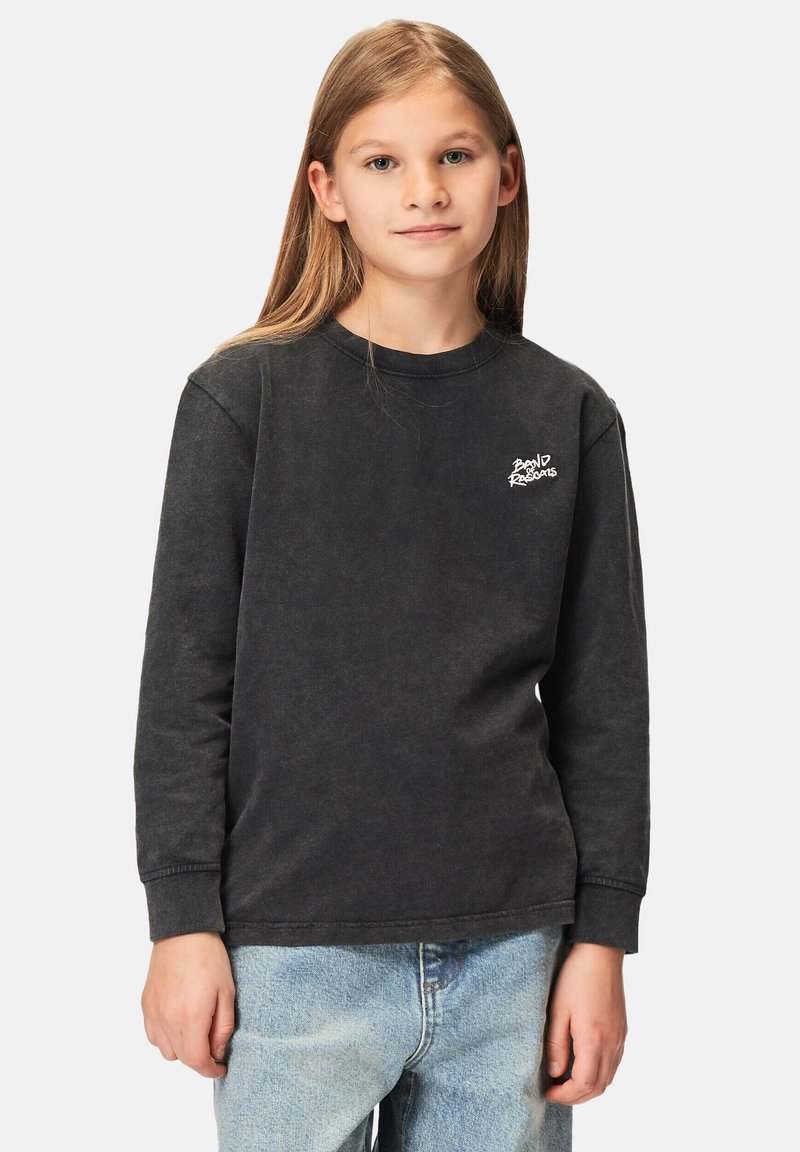 Musta pitkähihainen puuvillapaita, jossa on pyöreä pääntie ja ribbausrannekkaita, ja vasemmalla puolella valkoinen brodeerattu logo.