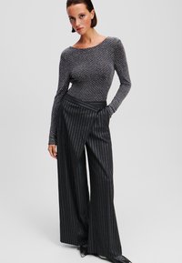Zwart en zilver langemouwen bodysuit gecombineerd met hoge zwarte pinstripe wijde broek, met een gladde textuur en een aansluitend ontwerp.