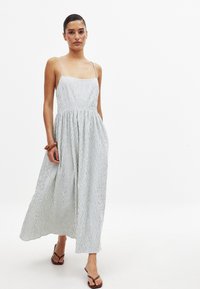 Robe midi rayée en bleu et blanc, avec des bretelles spaghetti, un corsage ajusté et une jupe fluide. Fabriquée dans un tissu léger et texturé.