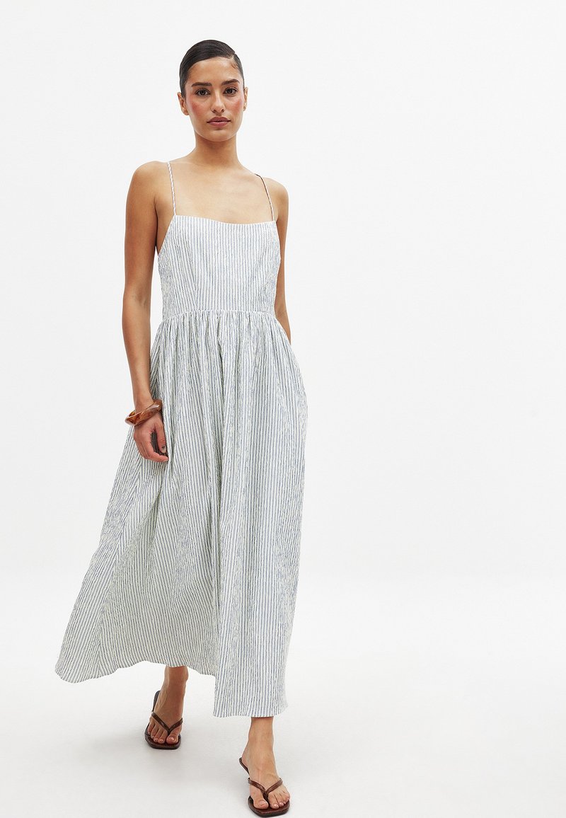 Robe midi rayée en bleu et blanc, avec des bretelles spaghetti, un corsage ajusté et une jupe fluide. Fabriquée dans un tissu léger et texturé.