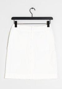 Jupe en denim blanc suspendue à un cintre noir, comportant une coupe droite, des poches avant et un design épuré et simple.