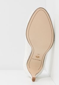 Semelle d'une chaussure blanche à lacets pour femme avec un petit talon, taille 36, nom de la marque "Tamaris" visible sur la semelle.
