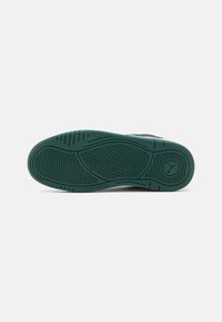 Suola in gomma verde per sneakers, con schemi di grip testurizzati e logo in rilievo. Piana con bordi arrotondati e battistrada definito per la trazione.