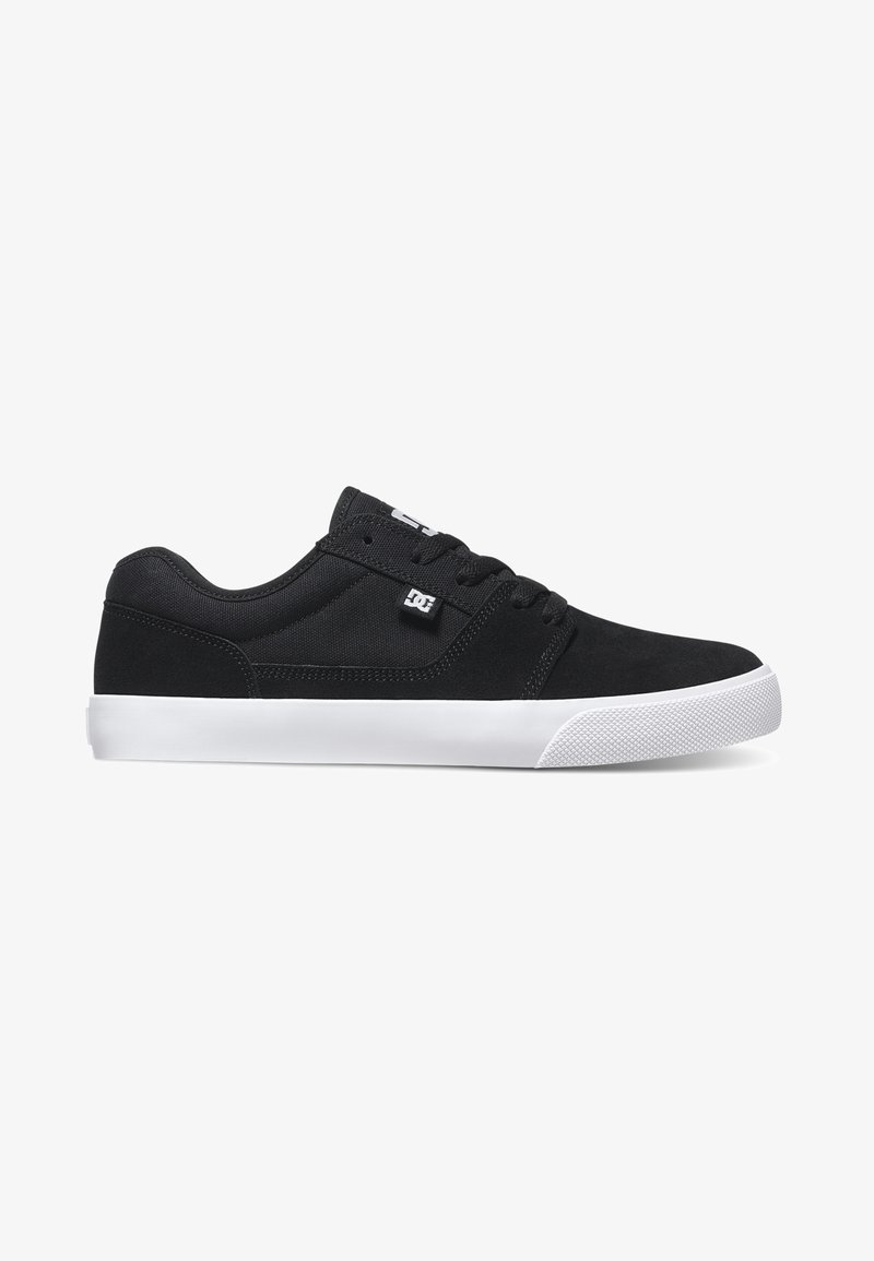Black skate shoes made of suede and textile, featuring a low profile, white rubber sole, and textured toe cap. Logo on side.