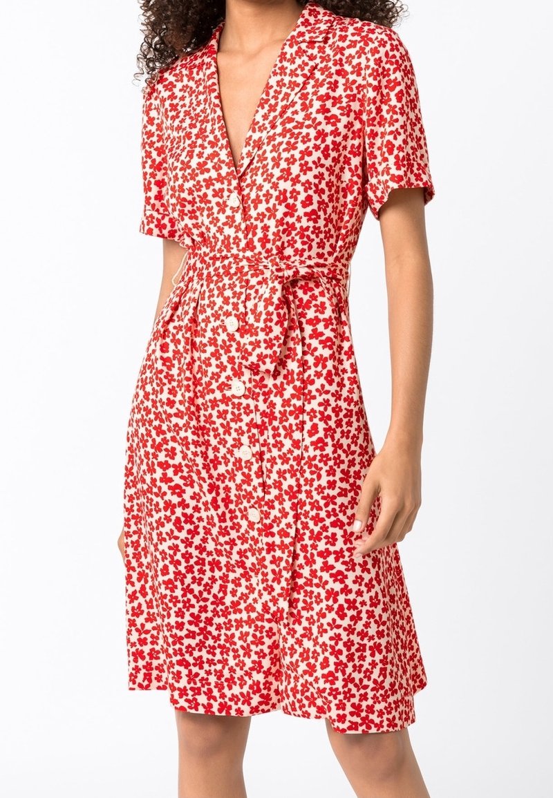 Czerwona i biała sukienka w kwiaty z krótkimi rękawami, zapięciem na guziki z przodu i wiązanym pasem. Lekki materiał, luźny krój i długość do kolan.