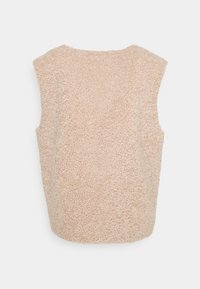 Beige ärmlös topp av texturerat fleece-material, med en rundad halsringning och en löst sittande passform. Inga synliga knäppningar eller dekorationer.