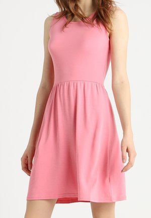 Robe rose sans manches, longueur aux genoux, avec corsage ajusté et jupe froncée portée par une personne sur un fond uni.