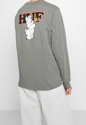 Long-sleeve grey T-shirt featuring a cartoon bunny holding a slice of pizza and "HUF" in orange text on the back. Soft cotton material.