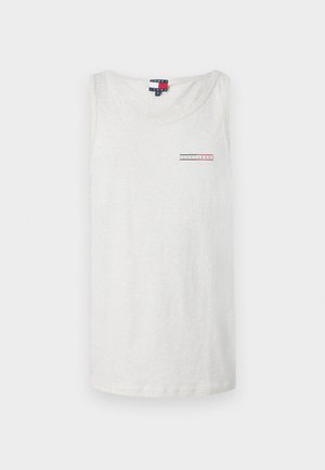 Světle šedý tílko vyrobené z měkké bavlny, s malou červenou a modrou nášivkou na levé části hrudi. Kulatý výstřih a bezrukávový design.