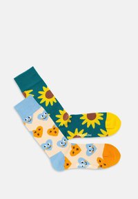 Farverige sokker med et gult solsikke-design på en teal baggrund og et fantasifuldt fuglemønster på en lys baggrund med orange accenter.