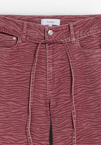 Pantalons bordeaux avec un motif rayé zèbre ; dotés d'une fermeture à bouton, de passants de ceinture et d'un lien en tissu, fabriqués en denim doux.