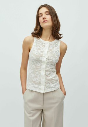 Weißes Spitzen-Top mit Blumenmuster, rundem Halsausschnitt und Knopfleiste vorne, kombiniert mit beigen maßgeschneiderten Hosen.