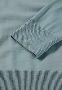Hellblauer gestrickter Pullover mit gerippten Bündchen und Saum. Glatte Textur mit einer Mischung aus feinen und dickeren Garnen in horizontalen Streifen.