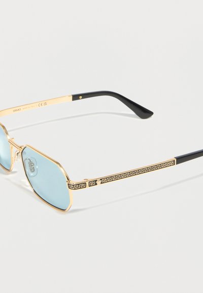 Χρυσά γυαλιά με μπλε κεκλιμένους φακούς και μαύρες άκρες στα σκέλη, με μαύρο μοτίβο ελληνικού κλειδιού και έμβλημα Μέδουσας στα σκέλη.