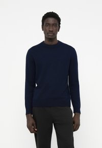 Navy blue knit sweater with a round neckline, long sleeves, and ribbed cuffs and hem. Soft texture with a minimalistic design.