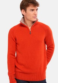 Roter Strickpullover mit einem Reißverschlusskragen, der ein heller gefärbtes Innenfutter sowie gerippte Bündchen und Saum aufweist.