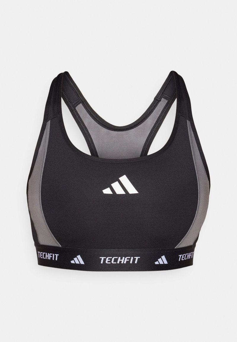 Sujeción deportiva negra con acentos grises, paneles de malla y una banda elástica ancha que presenta "TECHFIT" y el logo de Adidas en blanco. Diseño de espalda de nadadora.