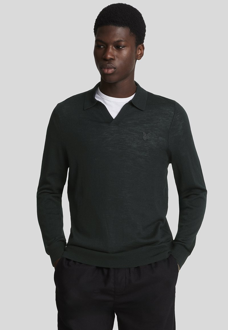 Dunkelgrüner langärmeliger Polo-Pullover mit V-Ausschnitt und einem dezenten Logo-Akzent. Hergestellt aus leichtem, strukturiertem Stoff.