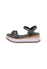 Zwarte platform sandalen met een gebogen zool. Beschikt over een dubbelriemontwerp en decoratieve hardware. Gepuncteerde bovenkant met een zilveren en tan zool.