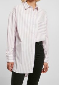 Chemise à rayures violet clair et blanc, à manches longues, avec une poche poitrine et un ourlet arrondi. Fabriquée dans un tissu lisse.