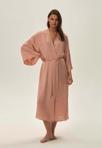Jasnoróżowy satynowy szlafrok z szerokimi rękawami, z paskiem w talii i długości do połowy łydki, z prostą, gładką fakturą.