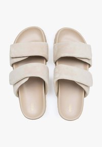 Beige suede slide sandals with two wide upper straps, a cushioned footbed, and a textured rubber sole. Logo printed on the insole.