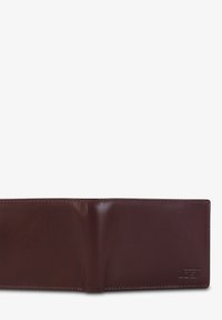 Cartera de cuero marrón con textura suave, diseño de dos pliegues y bordes cosidos. Presenta un logotipo prensado en la esquina inferior derecha.