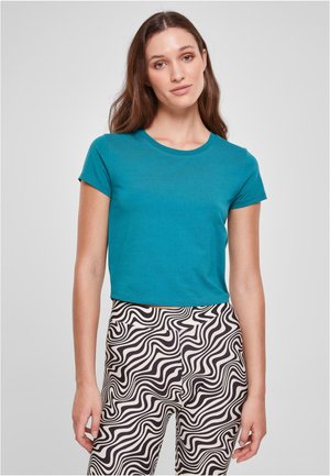 T-shirt teal à manches courtes avec un col rond, assortie à un pantalon à motifs ondulés noir et blanc, en tissu doux.