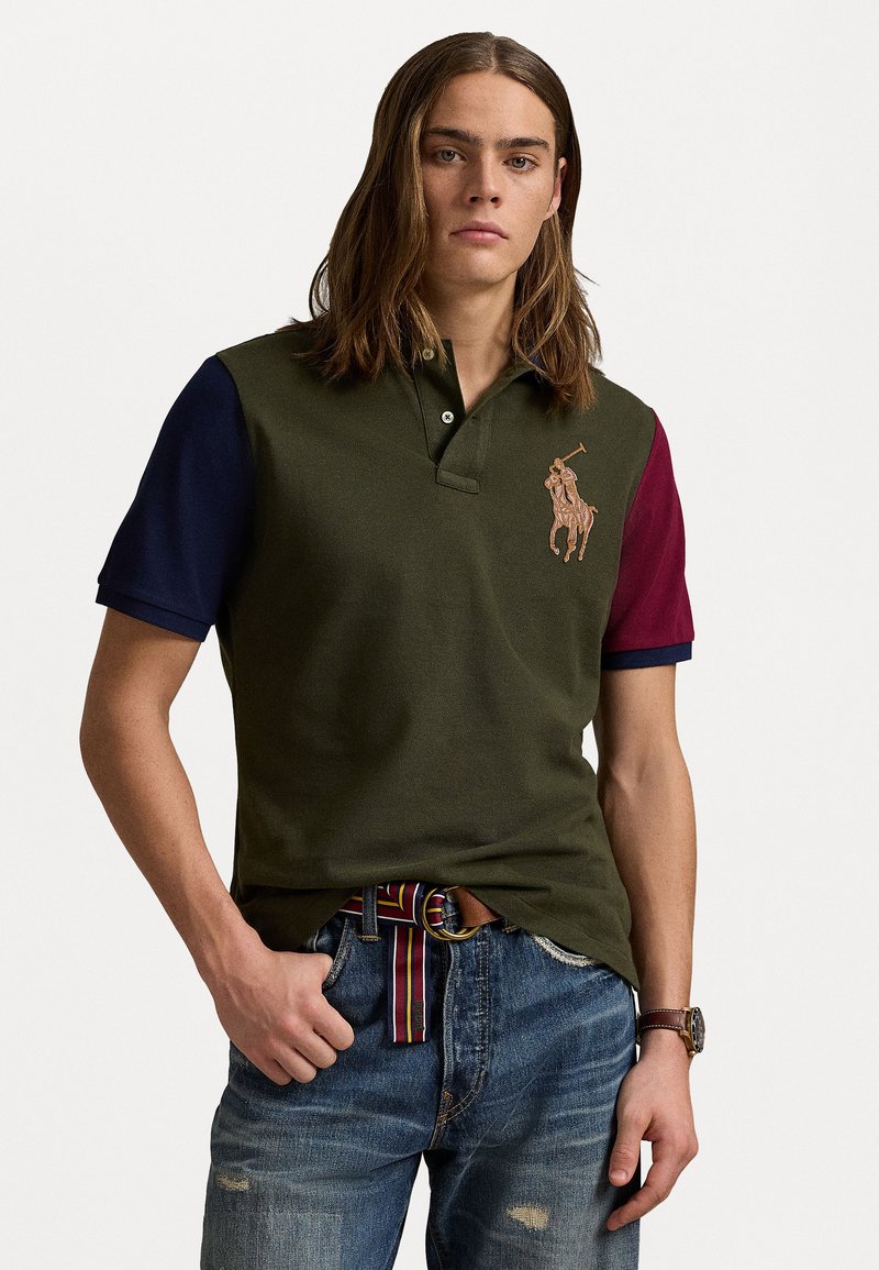 Polo shirt in olijfgroen met marineblauwe en bordeauxrode mouwen, voorzien van een bruin geborduurd logo, een knoopsluiting met twee knopen en een textuurstof.