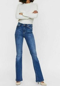 Jean en denim bleu taille haute avec un design à jambe évasée. Comprend un style cinq poches et une fermeture à bouton métallique à la taille.