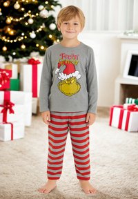 Maglioncino grigio a maniche lunghe con grafica del Grinch e testo "Feelin' Grinchy", abbinato a pantaloni da pigiama a righe rosse e grige. Indossato da un bambino in casa.