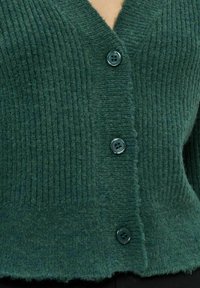 Cardigan verde scuro a costine con scollatura a V profonda, quattro bottoni scuri e finitura testurizzata con orlo grezzo.