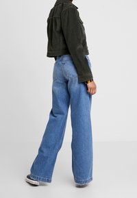 Czarna kurtka z korduroy o kroju krótkim oraz szerokie niebieskie dżinsy, z dopasowaną talią, luźnym fasonem i klasycznymi detalami szycia.