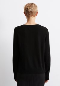 Schwarzer Strickpullover mit langen Ärmeln, geripptem Saum und Ausschnitt. Schlichtes Design, weiche Textur, Ansicht von hinten. Minimalistisches Erscheinungsbild.