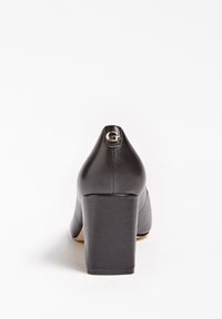 Chaussure à talons hauts en cuir noir avec un talon épais et un bout arrondi. Présente un emblème doré en forme de "G" à l'arrière. Texture lisse.