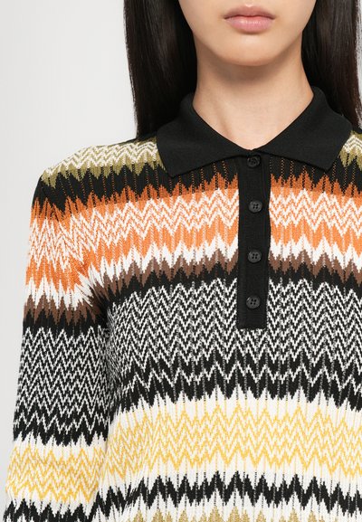 Polo shirt lavorato a maglia con un motivo a zigzag in arancione, nero, bianco, marrone e giallo, con un colletto nero e cinque bottoni.