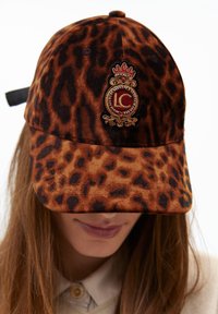 Berretto da baseball con stampa leopardata realizzato in tessuto morbido, con un logo ricamato in oro, rosso e nero. Visiera curva e cinturino regolabile.