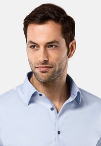 Lichtblauw overhemd met een gestructureerde kraag, contrasterende binnenafwerking en rode knopelementen. Gladde stof met een getailleerde pasvorm.