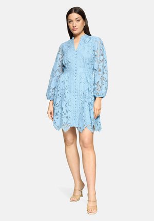 Jasnoniebieska sukienka koronkowa z długimi prześwitującymi rękawami, zapinana z przodu na guziki, z falowanym brzegiem. Tkanina ma kwiatowy wzór i teksturowane wykończenie.