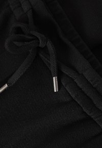 Svart tyg med dragsnodd, texturerad yta, metallände och synlig sömdetalj.