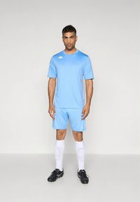 Camisa e calções atléticos azul celeste em material leve; meias brancas e chuteiras pretas com solas texturizadas; logótipo da Kappa no peito.
