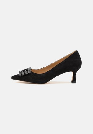 Schwarze Wildleder-Pumps mit hohem Absatz und spitzem Zehenbereich sowie einer dekorativen, mit Strass akzentuierten Schleife auf der Vorderseite. Verfügt über einen niedrigen Blockabsatz.