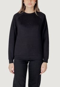 Felpa nera con collo rotondo e maniche lunghe a raglan. Tessuto sottile, polsini e orlo a costine, con un piccolo logo sul petto.