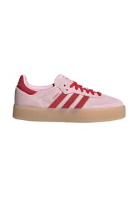 Lichtroze suède sneakers met rode accenten, voorzien van drie rode suède strepen, rode veters, een rond hoefijzer en een gumrubberen buitenzool.
