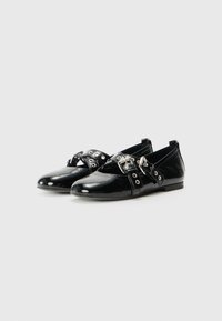 Black patent leather shoes with a low heel, featuring decorative buckle straps and grommet details. Smooth texture with a rounded toe shape.