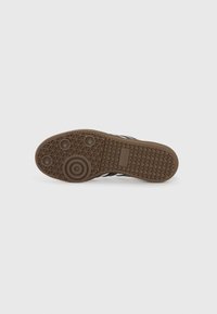 Rubber sneaker sole with a brown textured design, featuring circular and triangular patterns, with a logo imprint near the heel.