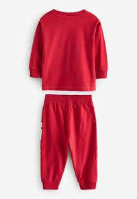 Costum din bumbac roșu format dintr-o cămașă cu mâneci lungi și guler rotund, împreună cu pantaloni jogger asortați, care au o talie elastică.
