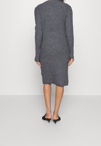 Robe en maille grise à manches longues, silhouette ajustée, longueur mi-mollet. Texture douce et détails côtelés sur le corsage.