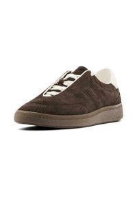 Sneaker in suede marrone con profilo basso, dettagli in bianco e suola in gomma testurizzata. Presenta un design con lacci e dettagli di cucitura visibili.
