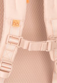 Bretelles de sac à dos rose clair avec boucles en plastique réglables et un panneau arrière rembourré en mesh, comportant une petite étiquette orange avec un logo.